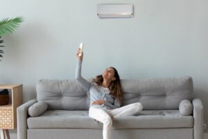 woman-sits-on-sofa-changes-temperature-of-mini-split-with-remote